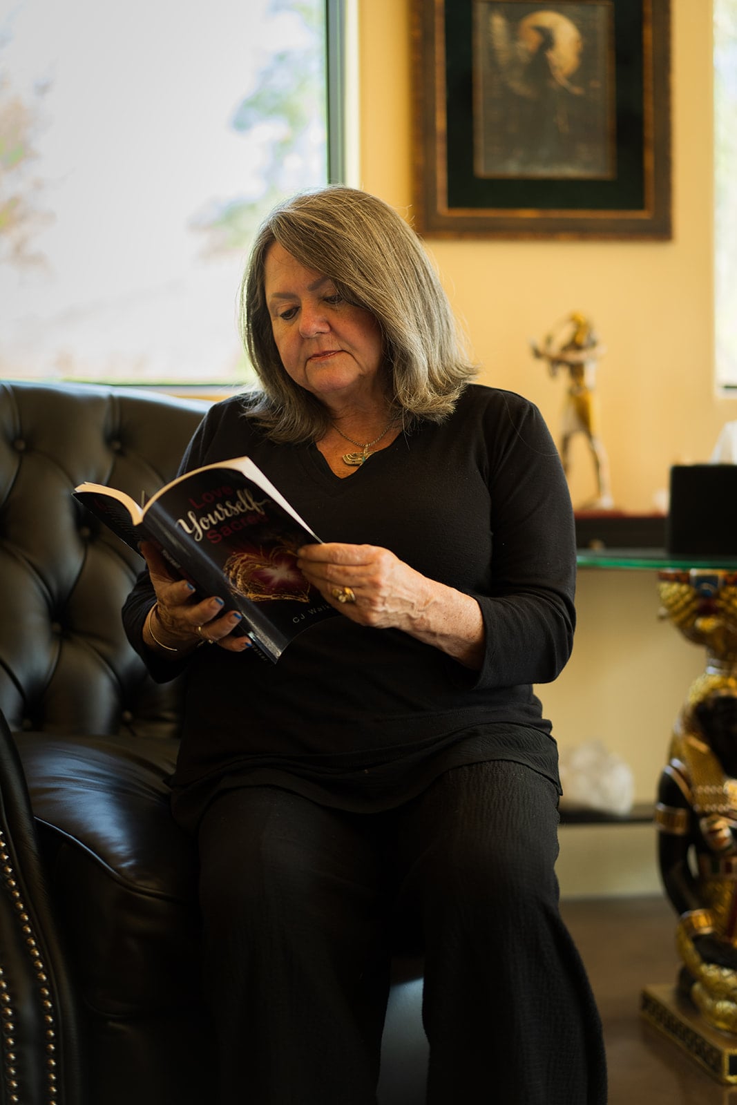 CJ Walker seated in the temple room, reading her book Love Yourself Sacred